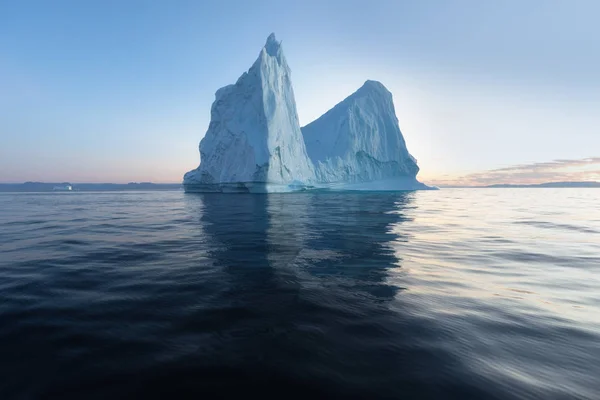 在日落时分 在一片有趣而蔚蓝的天空下 有照片和错综复杂的冰山 全球变暖在自然界中的影响 南极洲或格陵兰岛深蓝色海水中冰川融化的概念图像 — 图库照片