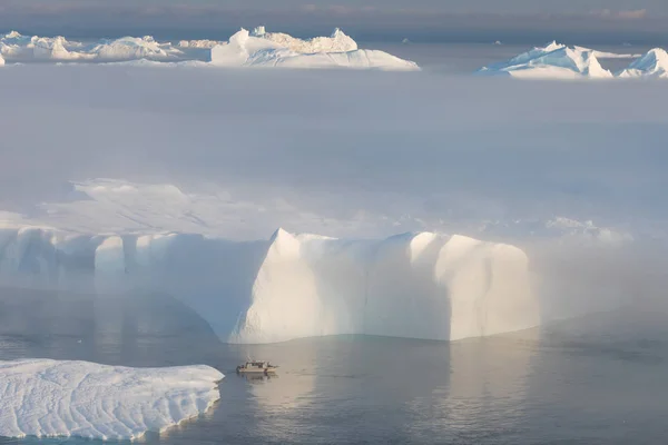 Photogenic and intricate iceberg under an interesting and blue sky during sunset. Effect of global warming in nature. Conceptual image of melting glacier in deep blue water in Antarctica or Greenland