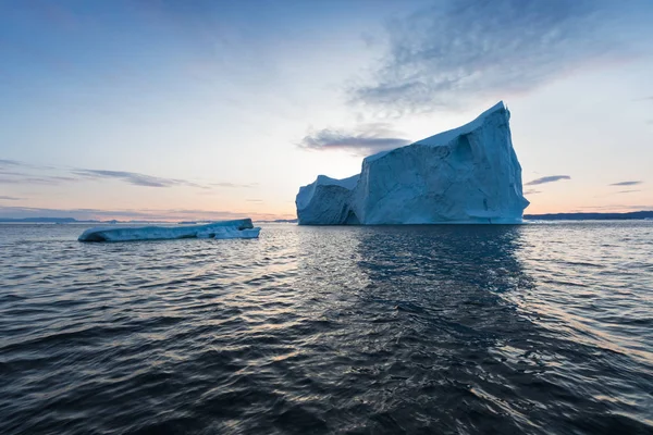 在日落时分 在一片有趣而蔚蓝的天空下 有照片和错综复杂的冰山 全球变暖在自然界中的影响 南极洲或格陵兰岛深蓝色海水中冰川融化的概念图像 — 图库照片