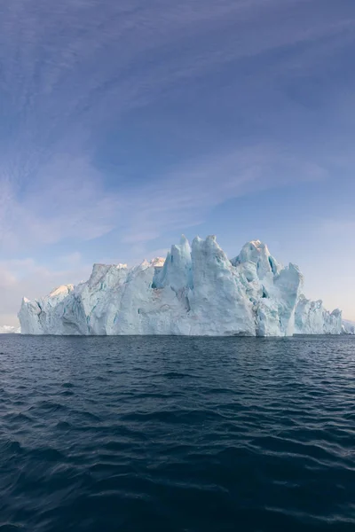 日没時の興味深く青い空の下でフォトジェニックで複雑な氷山 自然界における地球温暖化の影響南極やグリーンランドの深い青い水の氷河の融解の概念像 — ストック写真