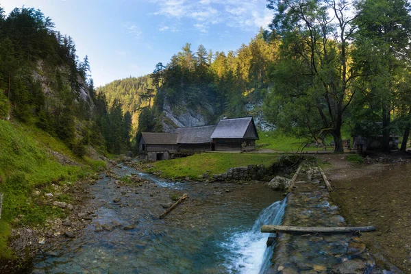 A historic grist mill building on the banks of Creek in Carpathian mountains, Slovakia, Europe. Old mill powered by water by using wooden water wheel. Sunn day in summer season.Romantic place.
