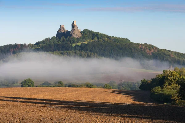 Ruins of old castle Trosky in Bohemian Paradise, Czech Republic. Ruins consist of two devasted towers on the woody hill. Morning landscape with misty atmosphere