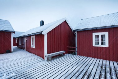 Reine, Norveç-10.10.2020 Geleneksel kırmızı ahşap evler Reine fiyort kıyısında. Vestvagoy Adası 'nın güzel kış manzarası. Lofoten Adaları, Norveç, Avrupa 'nın resimli sabah manzarası.