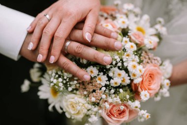 Gelin ve damat buket üzerinde elini tutarak