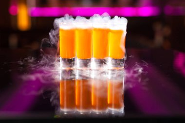 Yansıtıcı ayna masada duman ile dört portakal kokteyl çekim