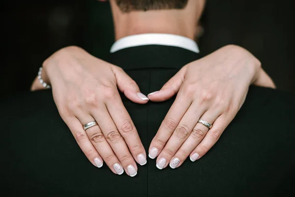 Руки нареченої з кільцями на спині нареченого — стокове фото