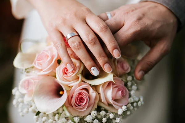 Bruid en bruidegom die hand op het boeket — Stockfoto