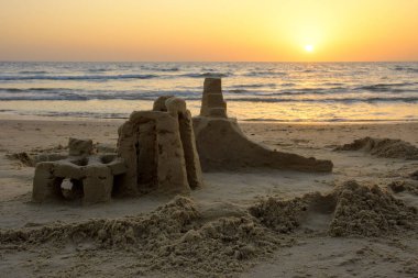 Akdeniz deniz dalgaları İsrail ile bulutsuz gökyüzünde parlak bir gün batımının fonunda sahilde kum Kulesi