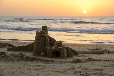 Akdeniz deniz dalgaları İsrail ile bulutsuz gökyüzünde parlak bir gün batımının fonunda sahilde kum Kulesi