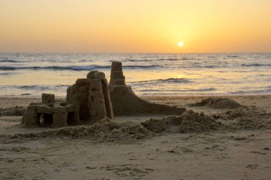 Akdeniz deniz dalgaları İsrail ile bulutsuz gökyüzünde parlak bir gün batımının fonunda sahilde kum Kulesi