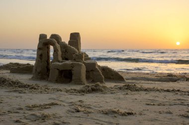 Akdeniz deniz dalgaları İsrail ile bulutsuz gökyüzünde parlak bir gün batımının fonunda sahilde kum Kulesi