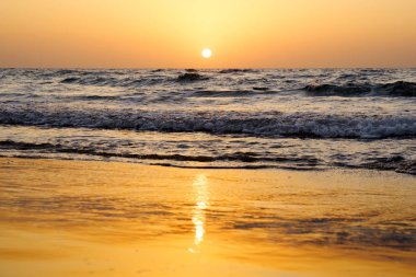 Dalgalar İsrail ile Akdeniz üzerinde bulutsuz gökyüzünde parlak bir günbatımı