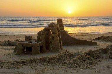 Akdeniz deniz dalgaları İsrail ile bulutsuz gökyüzünde parlak bir gün batımının fonunda sahilde kum Kulesi