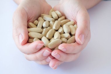 vitamin hapları Tıbbi preparatlar biyolojik hapları gri oval yalan bir kadın palmiye beyaz bir arka plan üzerinde kaotik bir sırada takviyeleri