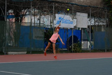 İsrail - Netanya, 27 Temmuz 2018: İsrail yarışmalarda sarayda top yapar vuruş büyük gürültü ile spor tenis Tenis swarty bir besleme oynayan kız genç çalışır