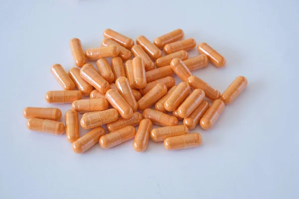 vitamins pills medications biological supplements orange oval tablets lie in a chaotic order on a white background