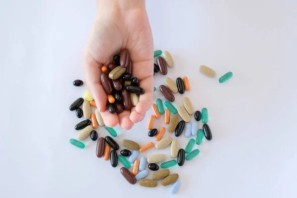 vitamins pills medications biological supplements pills multicolored oval round lie in a chaotic order on a white background on a female palm
