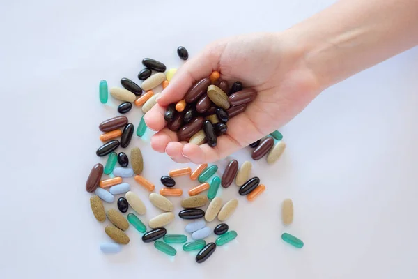 vitamins pills medications biological supplements pills multicolored oval round lie in a chaotic order on a white background on a female palm