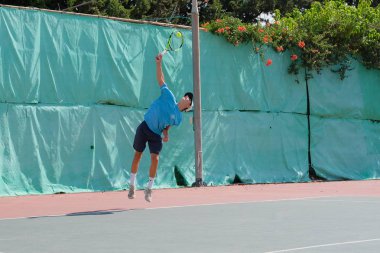 İsrail - Netanya, 27 Temmuz 2018: genç bir adam bir spor gömlek ve spor şort tenis kortunda tenis oynuyor