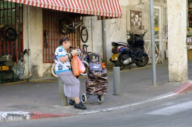 İsrail - Netanya, 03 Ekim 2017: kadın yaşlı bir sokak köşesinde oturur ve telefon görünüyor