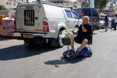 İsrail - Netanya, 13 Ekim 2017: özürlü bir yaşlı adam bir cep telefonu üzerinde konuşurken bir elektrikli tekerlekli sandalye
