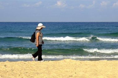 İsrail - Netanya, 14 Ekim 2017: plaj boyunca Akdeniz kıyısında yürüyen yetişkin kadın