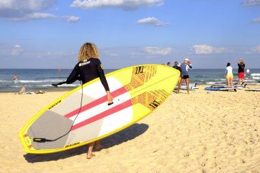 İsrail - Netanya, 14 Ekim 2017: sup tekne Akdeniz'de yüzmek için sahil boyunca yürüyen yetişkin kadın