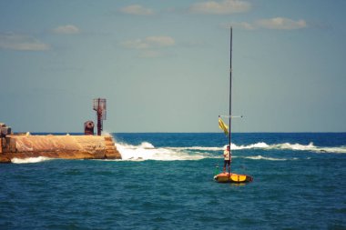 İsrail - Jaffa, 25 Eylül 2017: Akdeniz'de bir yelkenli bir erkekte kıyıdan yelken
