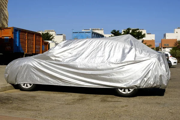 the car covered with a cover stands on the street