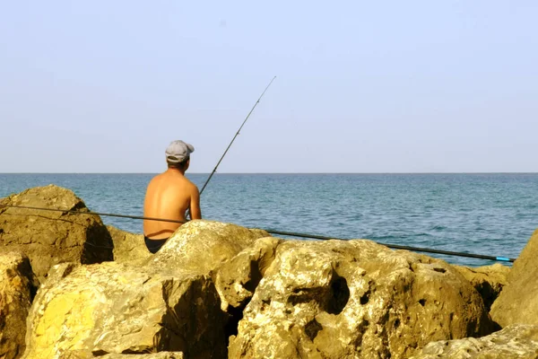 a man on the beach of a young fish for fishing