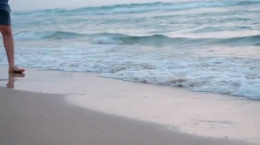 Genç bir çocuğun genç ayaklar gün batımından sonra Akdeniz pembe renk kıyılarında yürümek