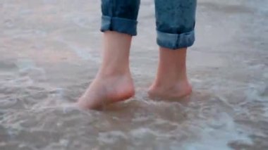 Genç bir kızın kadın bacakları gün batımından sonra Akdeniz 'de pembe denizin kıyısında yürüyor