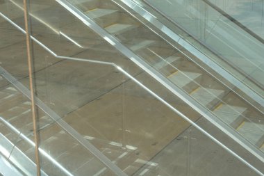 Bir alışveriş merkezinde camların arkasında yürüyen merdiven.