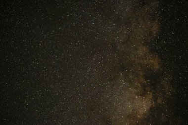 Samanyolu galaksisinin gece gökyüzünde yıldızlı renkli bir görüntüsü.