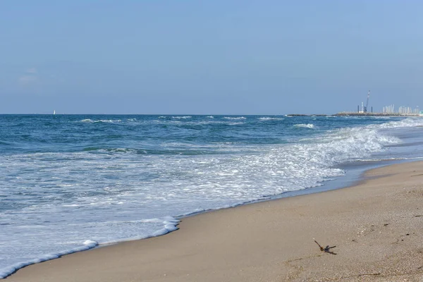 Deniz, mavi gökyüzünün altında beyaz köpük mavi dalgalar.