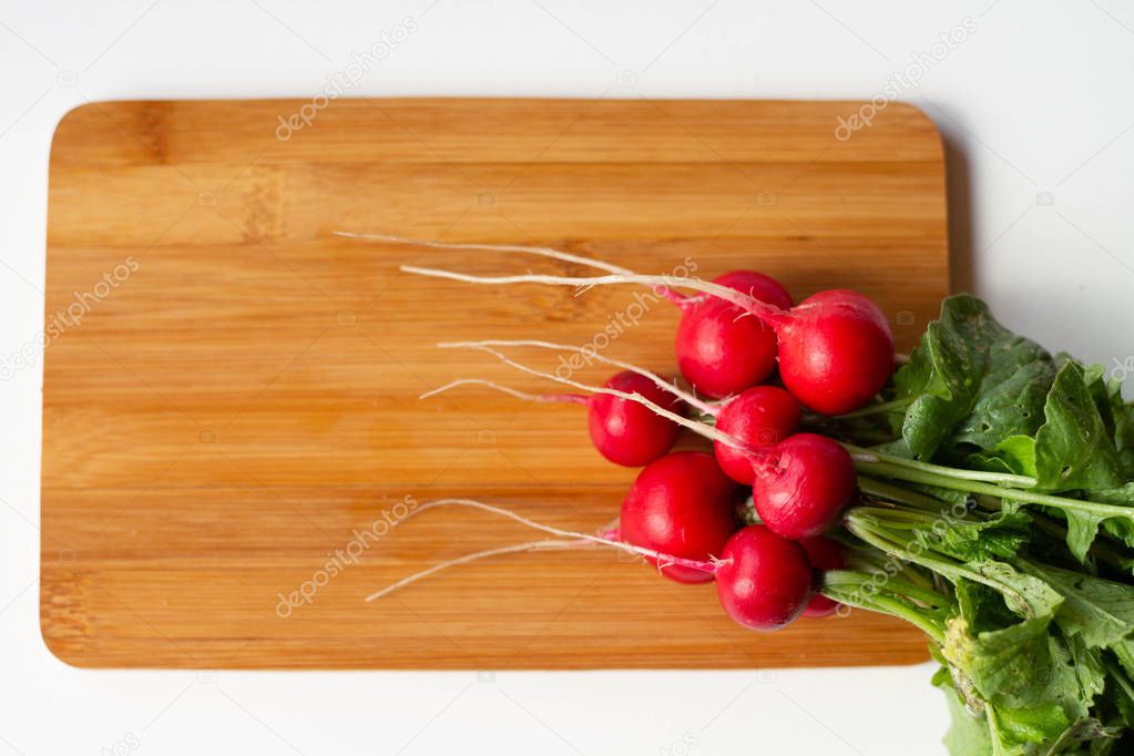 Fresh washed red round radishes on the wooden bamboo cutting board