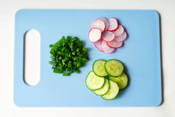 Sliced radish, Cucumber, Green onion on the blue slate board, top view. Ingredients for vitamin spring salad