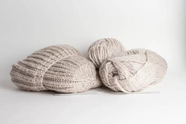 Hilados de lana en rollos, una bola de lana y un sombrero de punto hecho a mano en una cesta — Foto de Stock