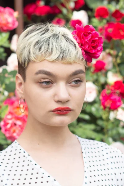 Beyaz bir bluz ve saçları bir gül ile güzel bir genç sarışın kız inanılmaz bir yaz arka planda bir gül bahçesinde duygularını ifade eder. Kız kırmızı castanets ile oynuyor.