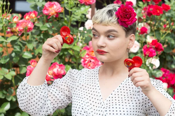 Beyaz bir bluz ve saçları bir gül ile güzel bir genç sarışın kız inanılmaz bir yaz arka planda bir gül bahçesinde duygularını ifade eder. Kız kırmızı castanets ile oynuyor.