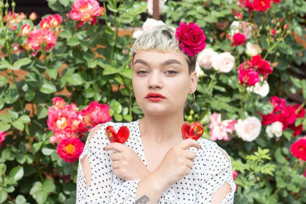 Beyaz bir bluz ve saçları bir gül ile güzel bir genç sarışın kız inanılmaz bir yaz arka planda bir gül bahçesinde duygularını ifade eder. Kız kırmızı castanets ile oynuyor.