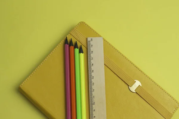 Коллекционный набор канцелярских принадлежностей имеют желтую тетрадь, цветные карандаши, линейку, изолированные на желтом фоне . — стоковое фото