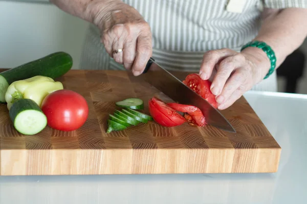 Senior or older woman cooking salad in kitchen. Healthy food concept. Healthy lifestyle. Grandma prepares a healthy meal for her grandchildren.