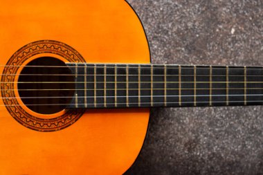Ahşap altı telli gitar. Beton arka planda yatan gitarın yakın çekim