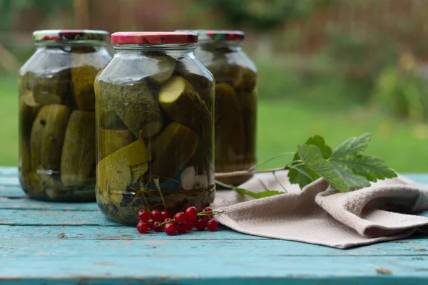 Homemade canned cucumbers in a jars on a blue wooden background, harvesting vegetables, pickles. Fresh and pickled cucumbers, homemade preserved vegetables — Stock Photo, Image