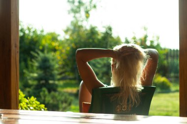 Kiev, Ukrayna, 07.27.2109 -Bir kadın batan güneşbakar. onun sarı saçlarıdokunur. Arkadan bak. saçlarına dokunur. bahçeye bakan bir terasta.