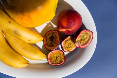 Taze tropikal meyveler, tutku meyve, papaya ve üst görünümünde bir pastel mavi arka plan üzerinde seramik plaka üzerinde muz. Vejetaryen diyet tatlısı. aralıklı açlık diyeti. Sağlıklı atıştırmalık.