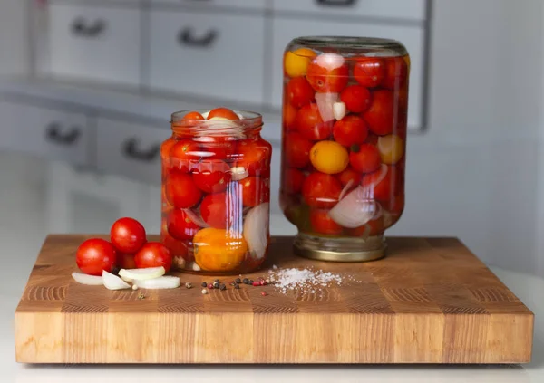 Tomates marinées dans des pots en verre sur une planche à découper en bois. Apéritif fait maison . — Photo