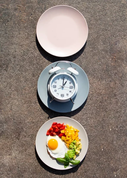 Intermittierendes Fastenkonzept mit leeren bunten Tellern. Zeit zum Abnehmen, zur Esskontrolle oder zum Diätkonzept. — Stockfoto