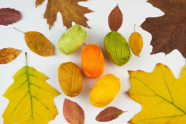 Balls of yarn in autumn colors on dried leaves background. — Stock Photo, Image